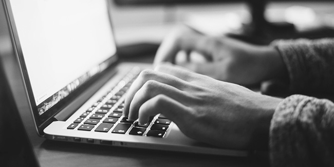 black and white photo of hands typing on a laptop keyboard